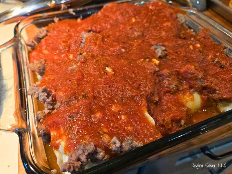 tomato sauce on top of the noodles and cooked meat