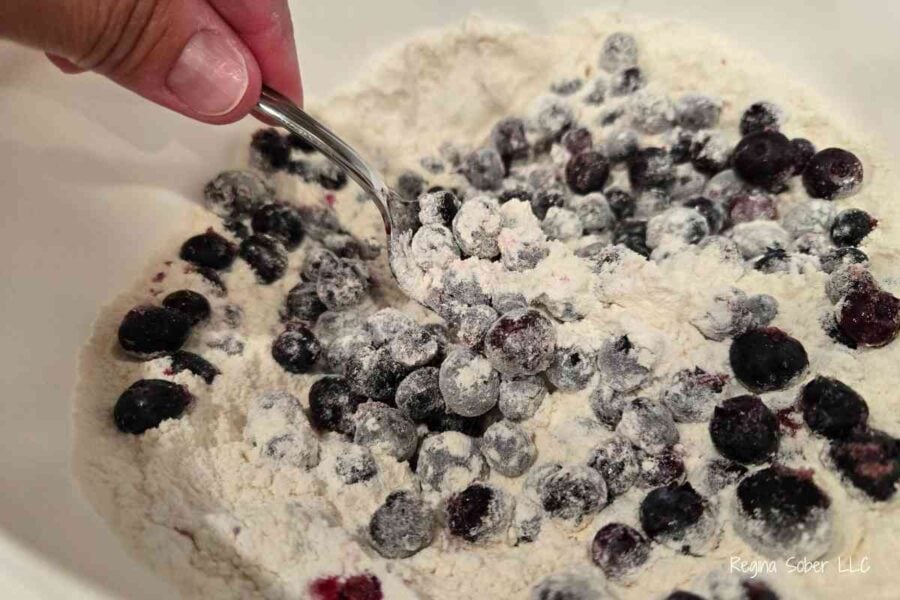 coating blueberries with the flour mixture to keep the blueberries from sinking to the bottom