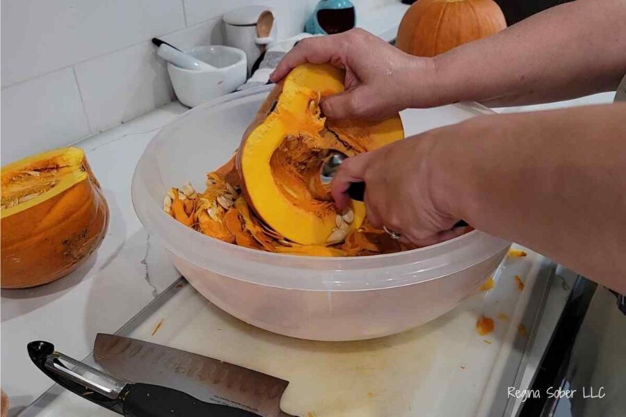 removing seeds with ice cream scoop in a bowl