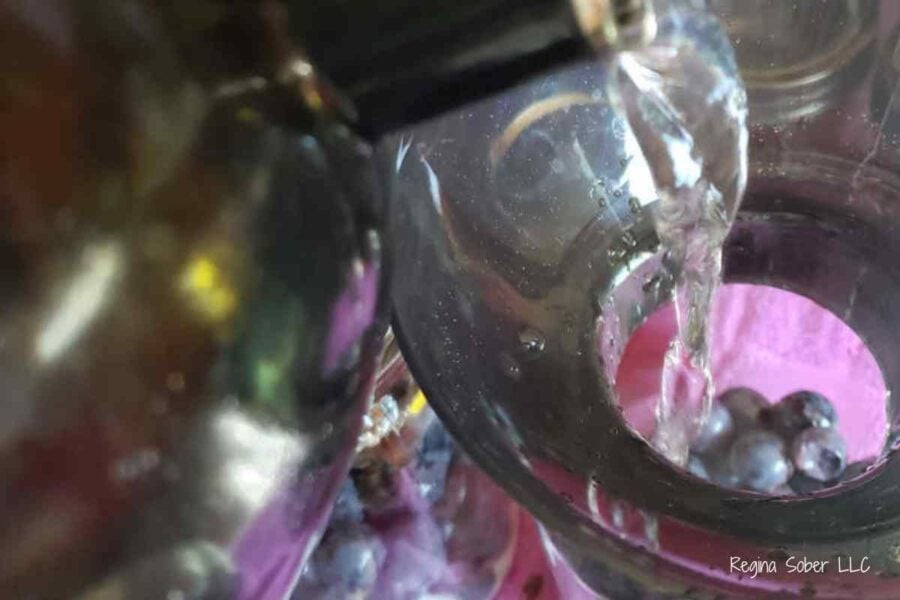 pouring hot water from tea kettle into hot jars with grapes