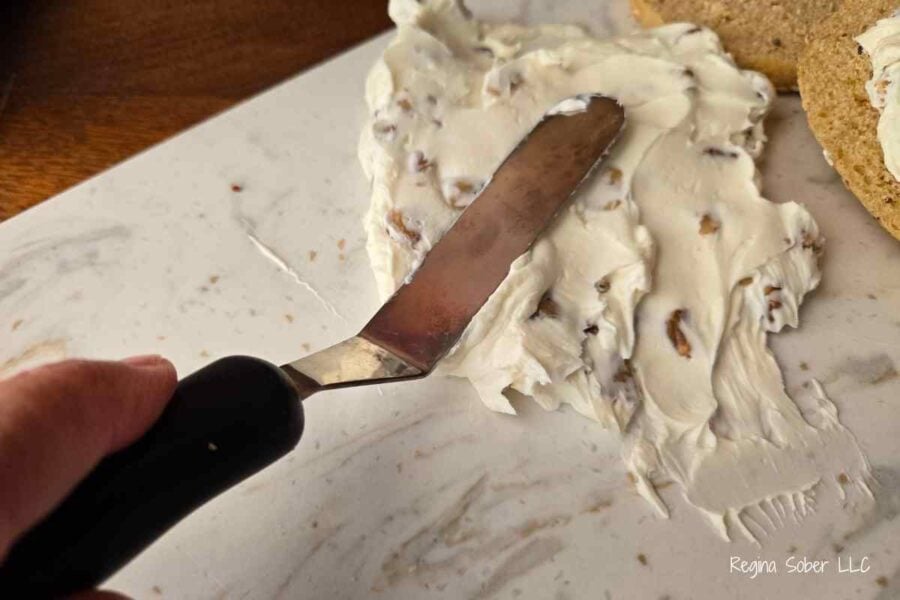 cream cheese spread onto charcuterie board toppings are honey walnut and cream cheese