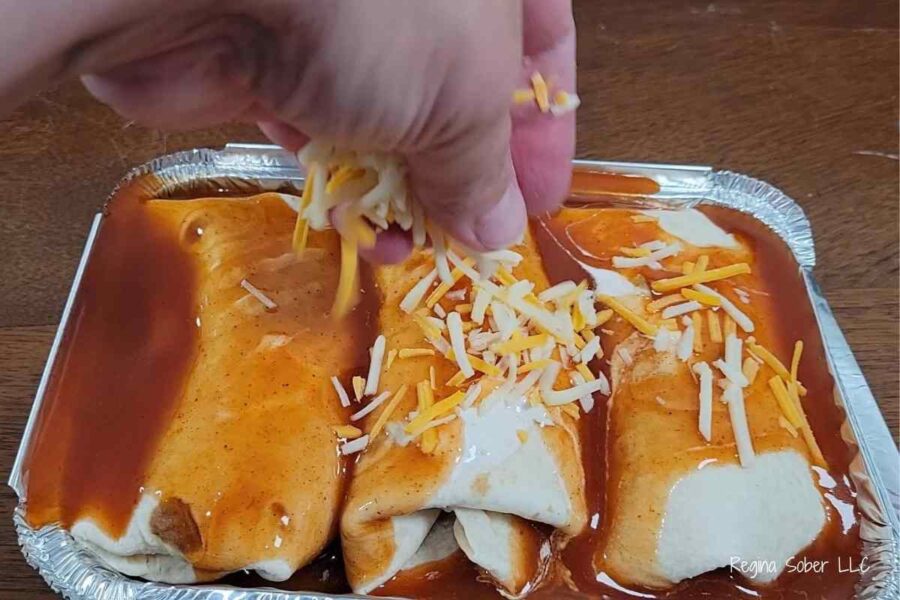 shredded cheese on top of enchiladas in flour tortillas