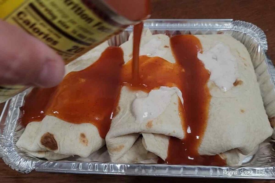 topping enchiladas with enchilada sauce in flour tortillas