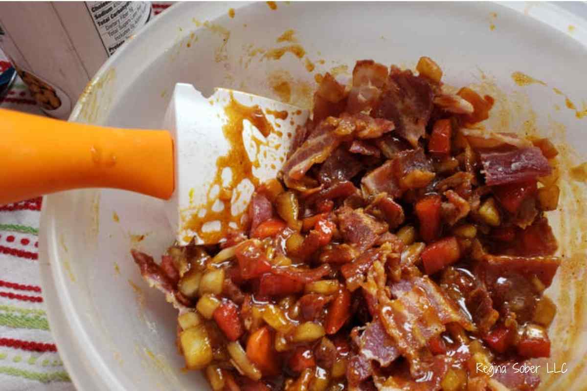 mixing in bacon into bowl of baked beans