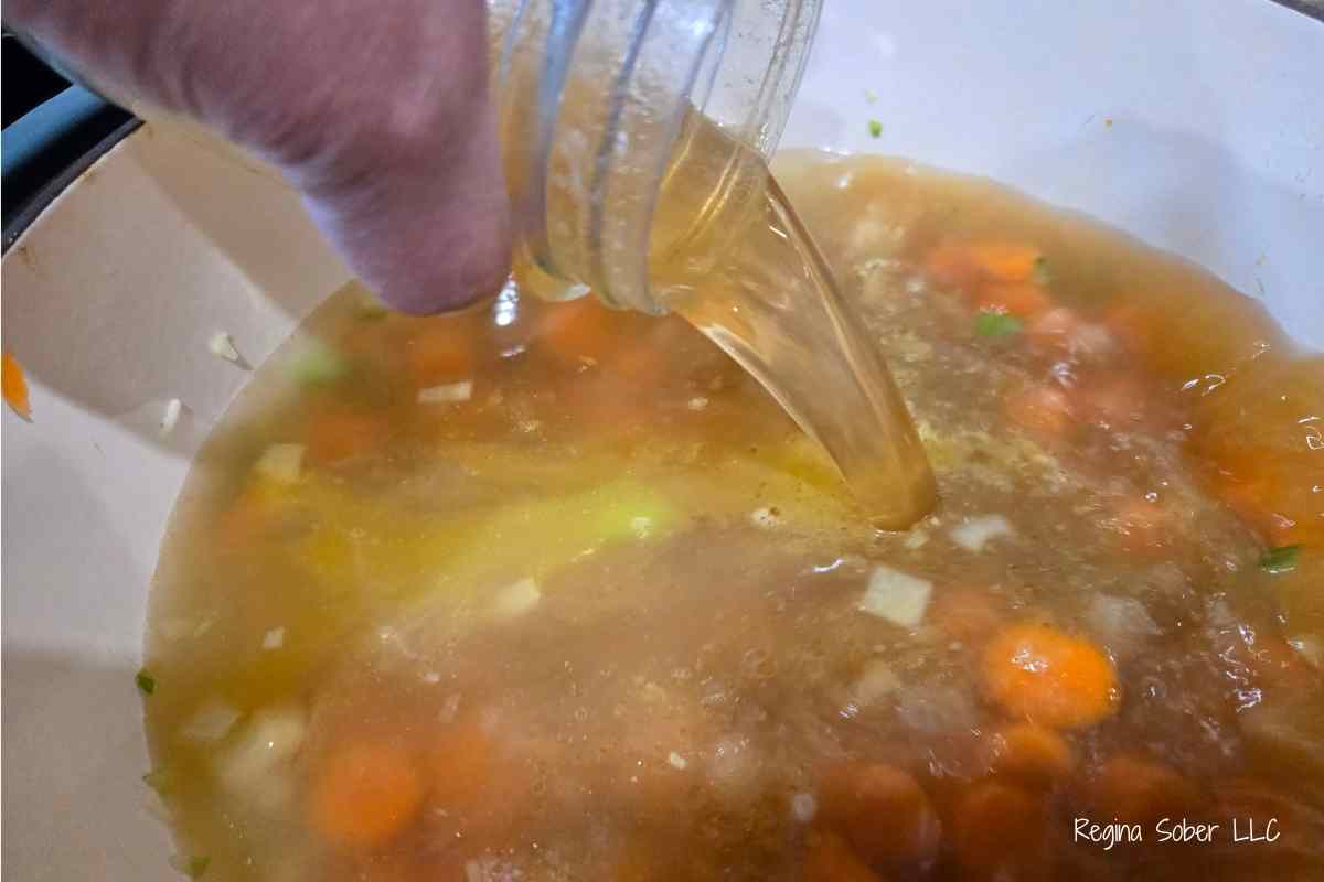 adding chicken stock to pot of carrots, celery and onions