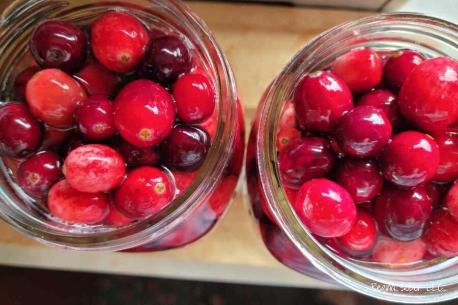full jars of fresh cranberries in quart jars