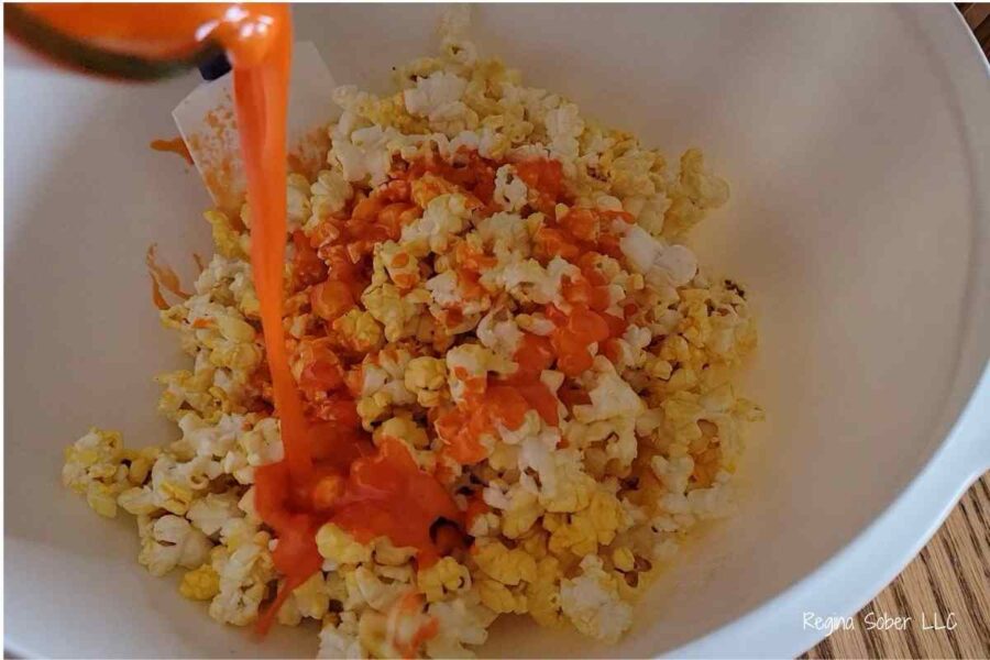 pour candy into popcorn and stir to coat evenly