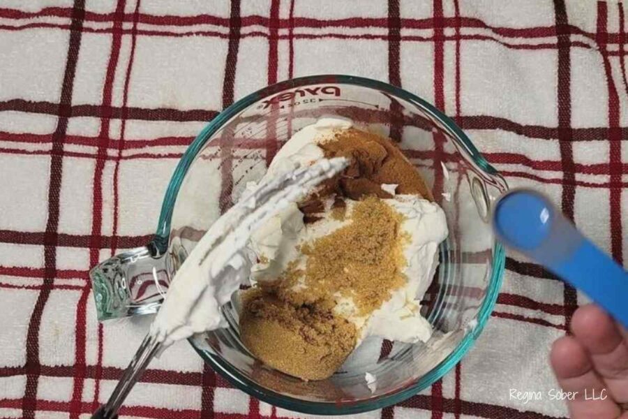 making fruit dip with brown sugar, sour cream and cinnamon in a bowl with a whisk