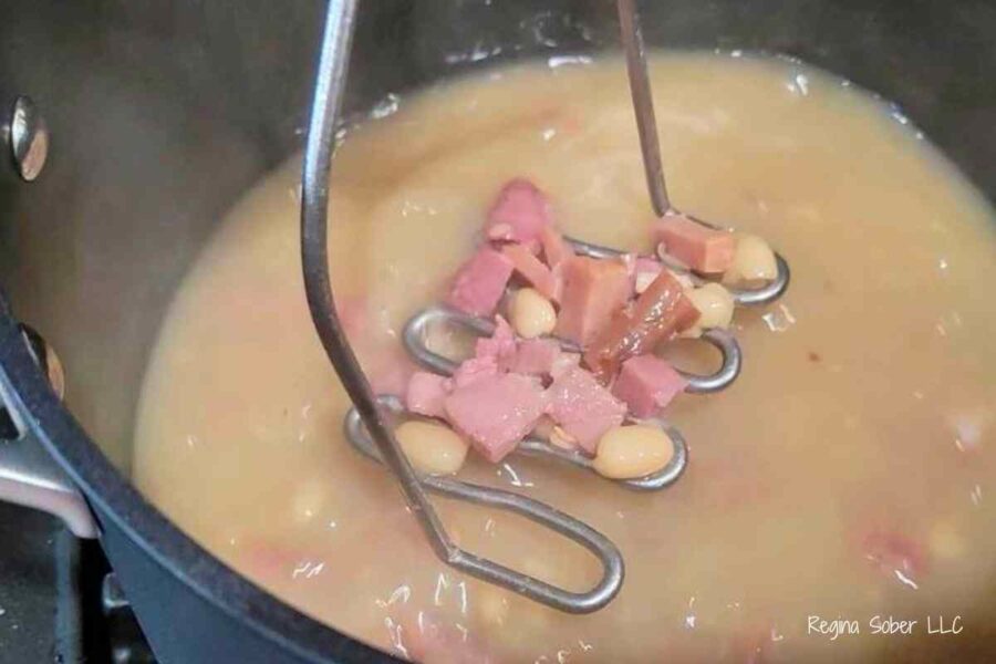 crushing canned beans with potato masher