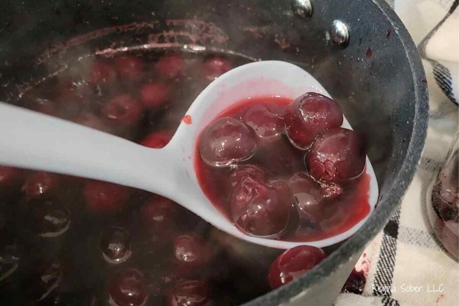 ladle with soaked cherries waiting to go in a jar