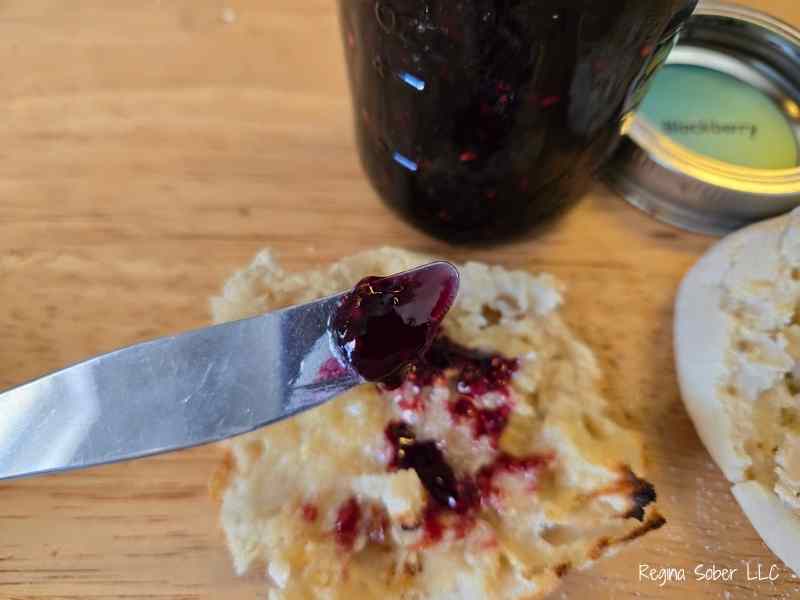putting blackberry jam on toasted English muffins for breakfast or snacks