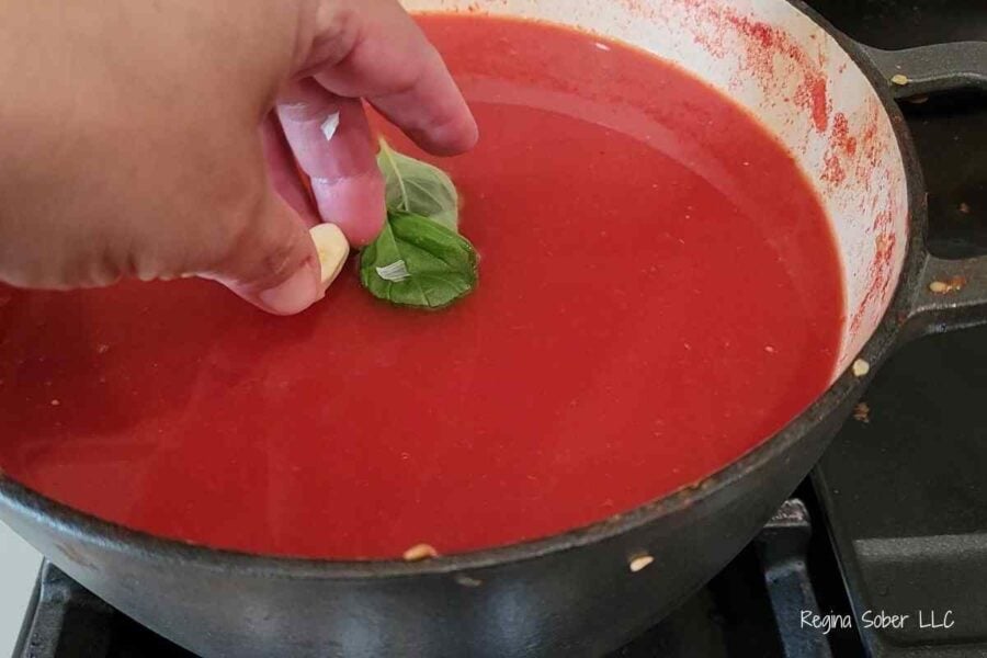 large pot with basil and garlic making own homemade tomato paste
