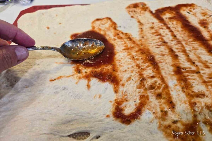 spread a thin layer of pizza sauce on dough