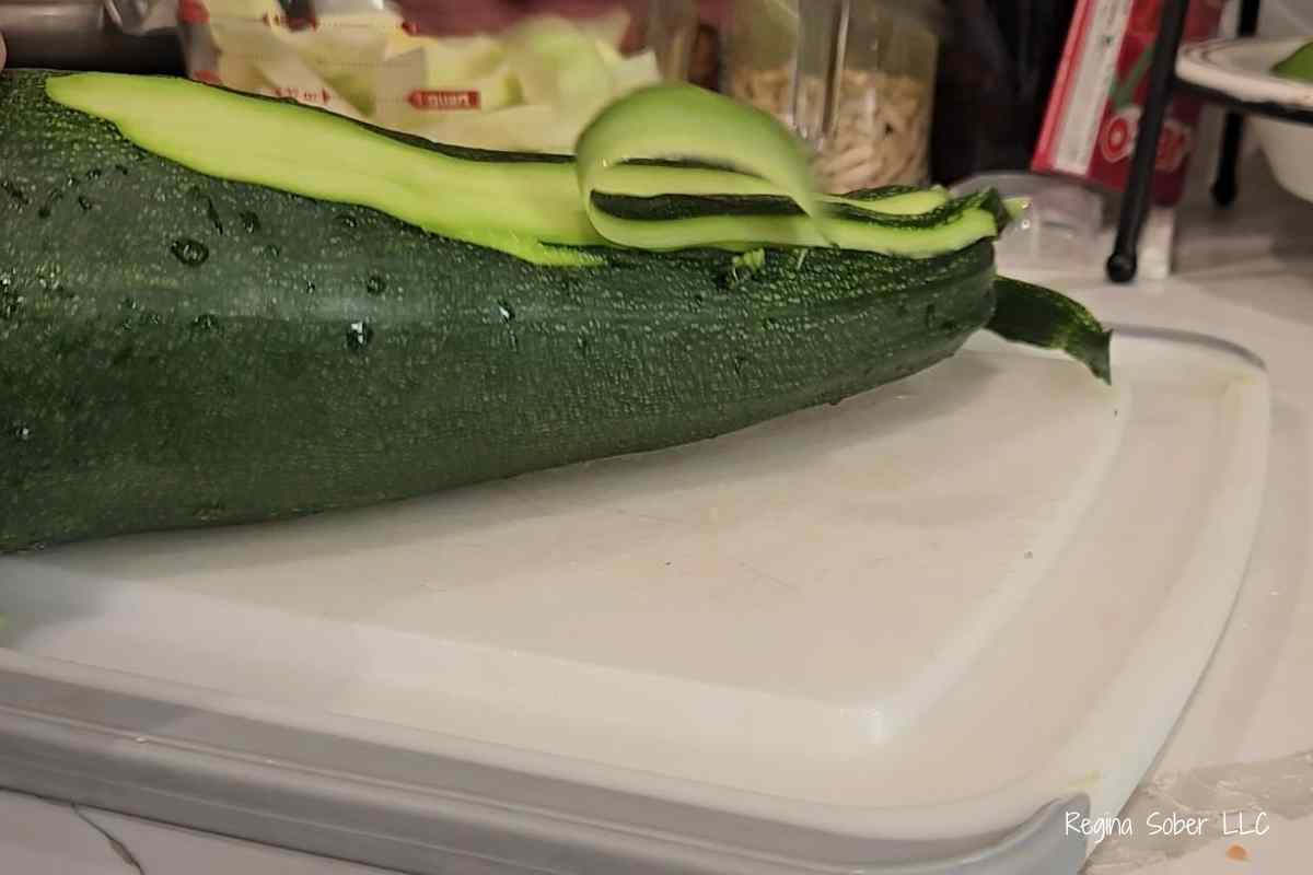 peeling huge zucchini on cutting board