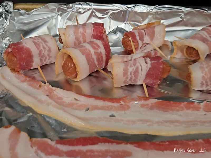 baking sheet covered in foil with wrapped sausages